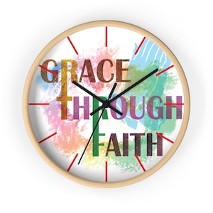 May include: A round wooden wall clock with a white face and red hour markers. The clock face features a colorful watercolor design with the words "GRACE THROUGH FAITH" in a rainbow of colors.