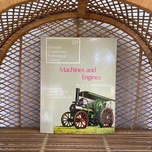 May include: A vintage book titled "Machines and Engines" from the Oxford Children's Reference Library. The cover shows a green and red steam engine illustration. The book is set against a woven wicker background.
