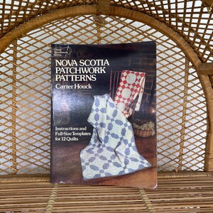 May include: A book titled "Nova Scotia Patchwork Patterns" by Carter Houck. The cover shows quilts in red and white, and blue and white. The book is part of the Dover Needlework Series and includes instructions and full-size templates for 12 quilts.