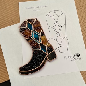May include: A stained glass diamond cowboy boot with brown, black, and teal glass pieces. The boot is outlined in copper and sits on a white paper with a pattern and the text "Diamond Cowboy Boot Pattern".
