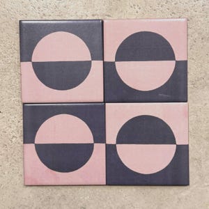 May include: Four square ceramic tiles with a geometric design. Each tile features a black and pink half circle pattern.