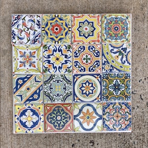 May include: A set of 16 colourful ceramic tiles with intricate geometric patterns in shades of blue, yellow, red, and green. The tiles are arranged in a grid pattern, creating a visually appealing mosaic.