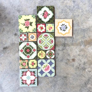 May include: A collection of square and rectangular ceramic tiles arranged in a cluster. The tiles feature various floral motifs, including roses and abstract botanical patterns, rendered in a palette of green, pink, yellow, red, and purple.