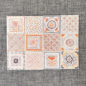 May include: A set of twelve square ceramic tiles arranged in a grid, each featuring distinct hand-drawn patterns in shades of orange, pink, grey, and black. The designs include floral motifs, geometric grids, heart shapes, and circular patterns.