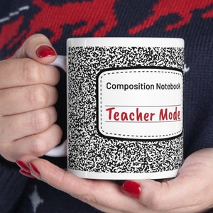 May include: White ceramic mug with a black and white composition notebook design. The mug has the text "Composition Notebook" and "Teacher Mode" in red.