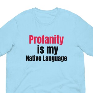 May include: Light blue t-shirt with the text "Profanity is my Native Language" in black and red lettering.