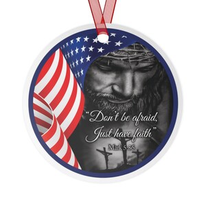 May include: A round, white ornament with a blue border. The ornament features a black and white image of Jesus with a crown of thorns, a red, white, and blue American flag, and the text "Don't be afraid, Just have faith" with the scripture reference "Mark 5:36".