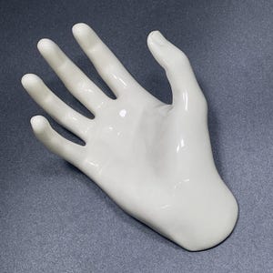 Puede incluir: Una taza de cerámica blanca con asa negra y el texto "But First, Coffee" en negro, con una fuente de estilo manuscrito. La taza está sobre una superficie blanca.