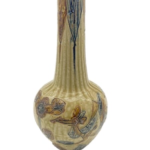 May include: A tall, slender ceramic vase with a bulbous base. The vase is decorated with a light brown, yellow, and blue floral pattern. The vase has a textured, ribbed surface.