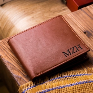 May include: A brown leather wallet with the initials "MZH" embossed on the front.