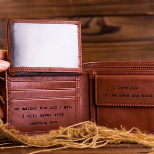 May include: A brown leather wallet with a personalized message inside. The message reads "No matter how old I get, I will never stop needing you" and "I love you to the moon and back".