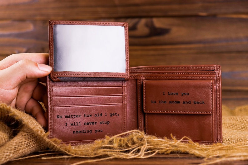 May include: A brown leather wallet with a personalized message inside. The message reads "No matter how old I get, I will never stop needing you" and "I love you to the moon and back".