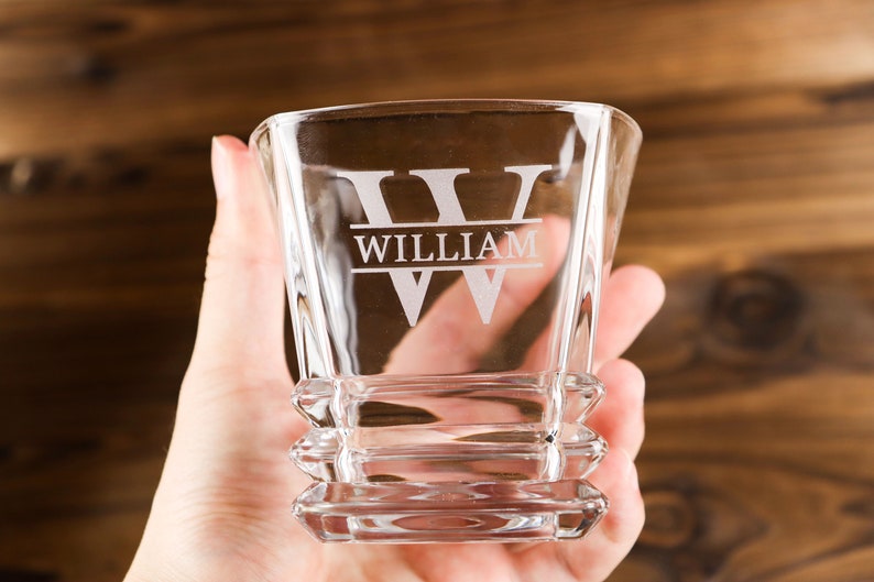 Puede incluir: Un vaso de rocas de vidrio transparente con base cuadrada y dise&ntilde;o personalizado. El vaso tiene la letra "W" grabada en la parte delantera con el nombre "William" debajo.