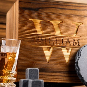 Puede incluir: Caja de madera con un dise&ntilde;o grabado personalizado que incluye el nombre "William" y la letra "W". La caja incluye dos vasos, un posavasos de pizarra y piedras de whisky.