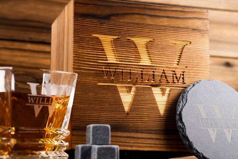 Puede incluir: Caja de madera con un dise&ntilde;o grabado personalizado que incluye el nombre "William" y la letra "W". La caja incluye dos vasos, un posavasos de pizarra y piedras de whisky.