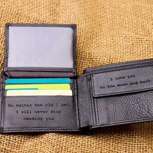 May include: A black leather wallet with a personalized message inside. The message reads "No matter how old I get, I will never stop needing you" and "I love you to the moon and back".