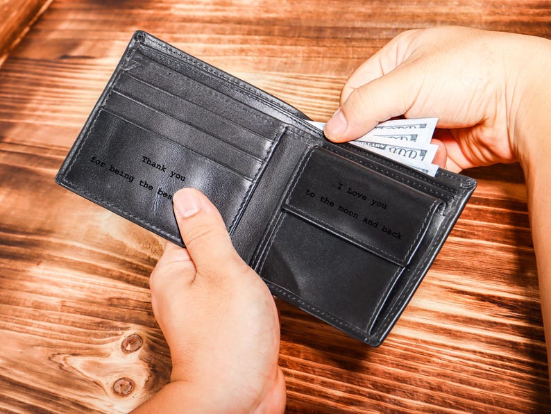 May include: A black leather wallet with a personalized message inside. The message reads "Thank you for being the best" on one side and "I love you to the moon and back" on the other side.