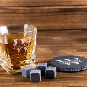 Puede incluir: Un vaso de whisky personalizado con el nombre "William" grabado en &eacute;l, junto con dos posavasos negros y cuatro piedras de whisky.