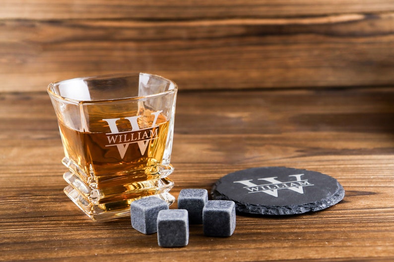 Puede incluir: Un vaso de whisky personalizado con el nombre "William" grabado en &eacute;l, junto con dos posavasos negros y cuatro piedras de whisky.