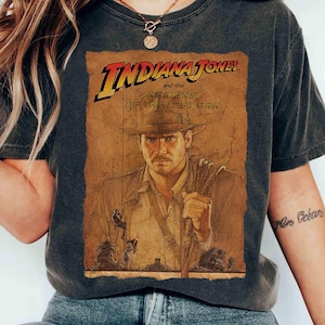 Op de afbeelding: Donkergrijs T-shirt met een vintage graphic uit de film "Indiana Jones and the Raiders of the Lost Ark". De graphic toont de titel van de film en een portret van de hoofdpersoon. Het shirt heeft een klassieke ronde hals en korte mouwen.