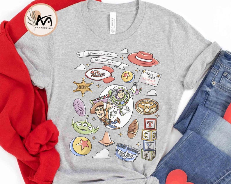 May include: A light gray t-shirt featuring cartoon characters and phrases from the movie Toy Story. The design includes Woody, Buzz Lightyear, and other characters, along with the text "You've got a friend in me."