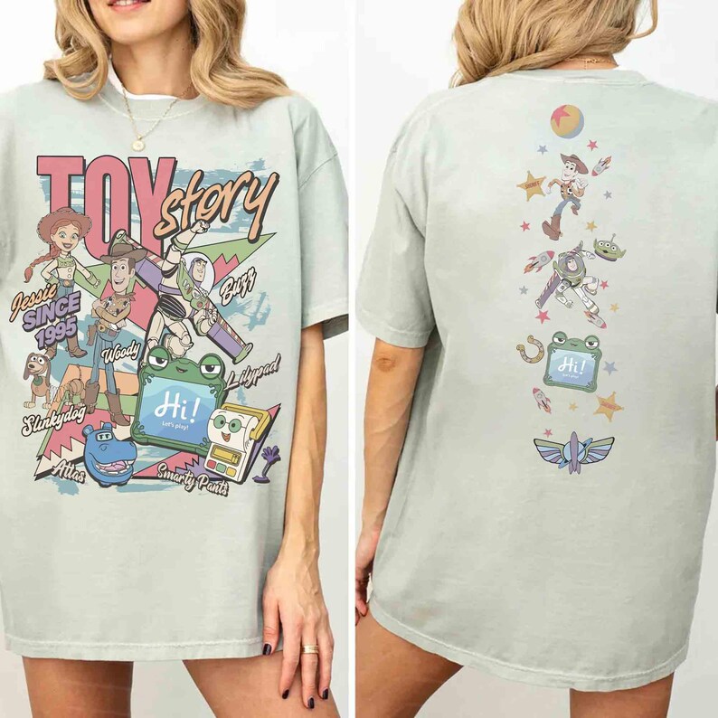 Op de afbeelding: Een lichtgroen t-shirt met Toy Story-personages op de voor- en achterkant. De voorkant toont Jessie, Woody, Buzz, Slinky Dog en anderen met de tekst Toy Story, Since 1995 en Hi. De achterkant toont een verticale rangschikking van personages.