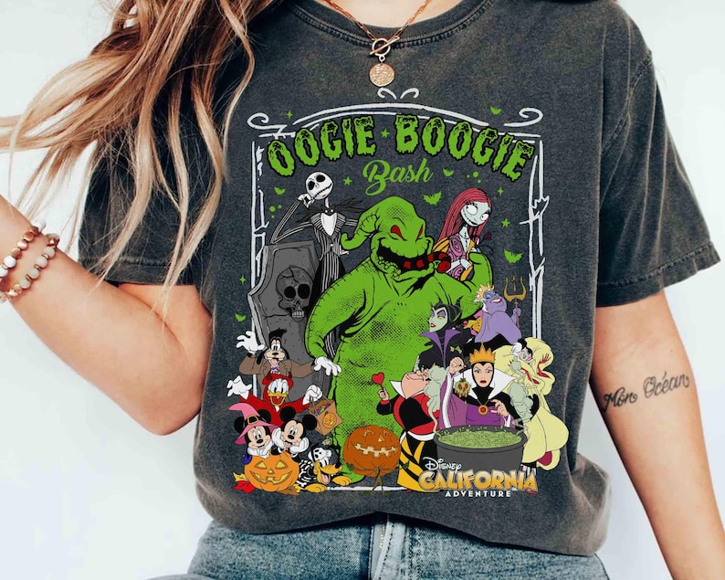 Puede incluir: Camiseta gris oscuro con un gr&aacute;fico de personajes de Disney, incluyendo Oogie Boogie, Jack Skellington y Mickey Mouse. El texto "Oogie Boogie Bash" y "Disney California Adventure" son visibles. La camiseta tiene un aspecto vintage y desgastado.