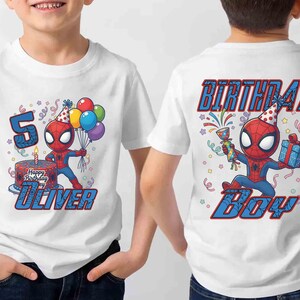 May include: White t-shirt featuring a cartoon Spider-Man design. The front displays a birthday cake, the number 5, and the name "Oliver." The back of the shirt says "Birthday Boy." The design includes colorful balloons and confetti.