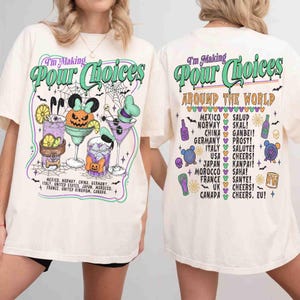 May include: An off-white t-shirt featuring a graphic print on the front and back. The front displays cocktails, a pumpkin, and the text "I'm Making Pour Choices." The back lists countries and drinking toasts with "I'm Making Pour Choices Around The World."