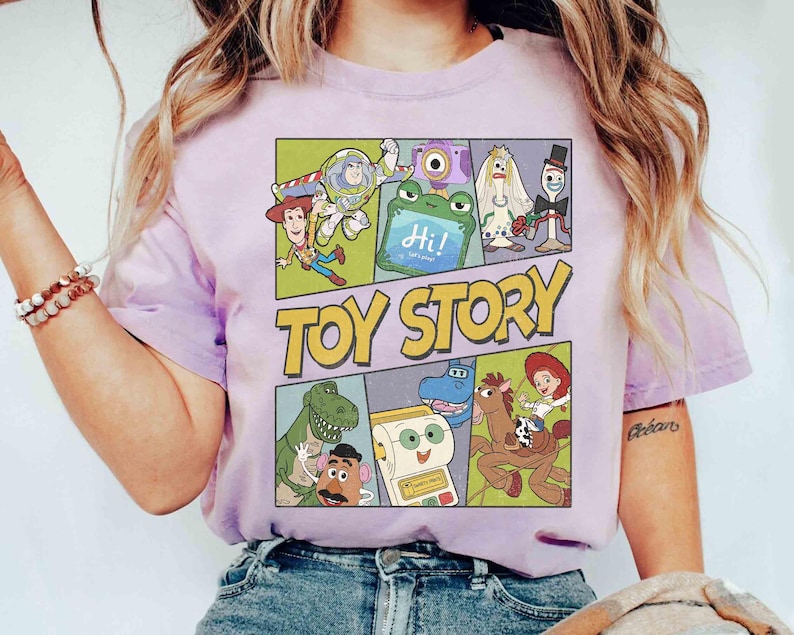Puede incluir: Una camiseta lila claro con un dise&ntilde;o gr&aacute;fico colorido de personajes de la pel&iacute;cula "Toy Story". El dise&ntilde;o presenta las palabras "Toy Story" en amarillo y personajes de dibujos animados en paneles separados, como un c&oacute;mic.