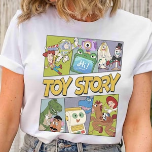 Puede incluir: Camiseta blanca con un gr&aacute;fico colorido de personajes de la pel&iacute;cula animada "Toy Story". El dise&ntilde;o incluye im&aacute;genes de Woody, Buzz Lightyear y otros personajes, con las palabras "Toy Story" en letras amarillas.