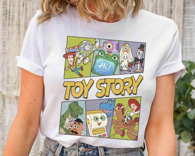 Puede incluir: Camiseta blanca con un gr&aacute;fico colorido de personajes de la pel&iacute;cula animada "Toy Story". El dise&ntilde;o incluye im&aacute;genes de Woody, Buzz Lightyear y otros personajes, con las palabras "Toy Story" en letras amarillas.