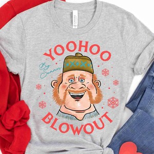 May include: A light gray t-shirt with a cartoon illustration of a smiling man wearing a hat. The text "YOO HOO BLOWOUT" is in red, with "By Sunner" in teal. Red snowflakes are scattered around the graphic.