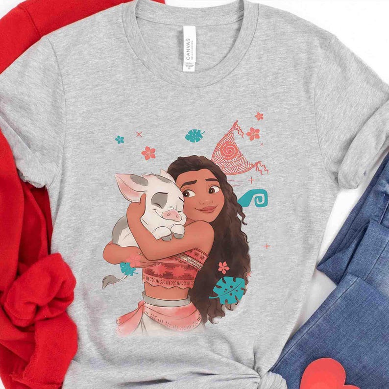 Puede incluir: Una camiseta gris jaspeado de manga corta con una ilustraci&oacute;n gr&aacute;fica de un personaje de pelo largo abrazando a un peque&ntilde;o cerdito. El dise&ntilde;o incluye peque&ntilde;os detalles florales y de hojas de colores, junto a un patr&oacute;n triangular sobre las figuras.