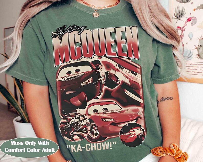 K&ouml;nnte beinhalten: Ein moosgr&uuml;nes T-Shirt mit einer Grafik von Lightning McQueen aus dem Film Cars. Das Design enth&auml;lt den Text "Lightning McQueen" und den Satz "KA-CHOW!". Das Shirt ist mit "Moss Only With Comfort Color Adult" gekennzeichnet.