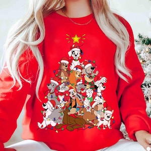Op de afbeelding: Een rode sweatshirt met een kerstboomontwerp van cartoonhonden met kerstmutsen en feestverlichting. Een gouden ster staat bovenaan. Dit is een feestelijk kledingstuk voor de feestdagen.