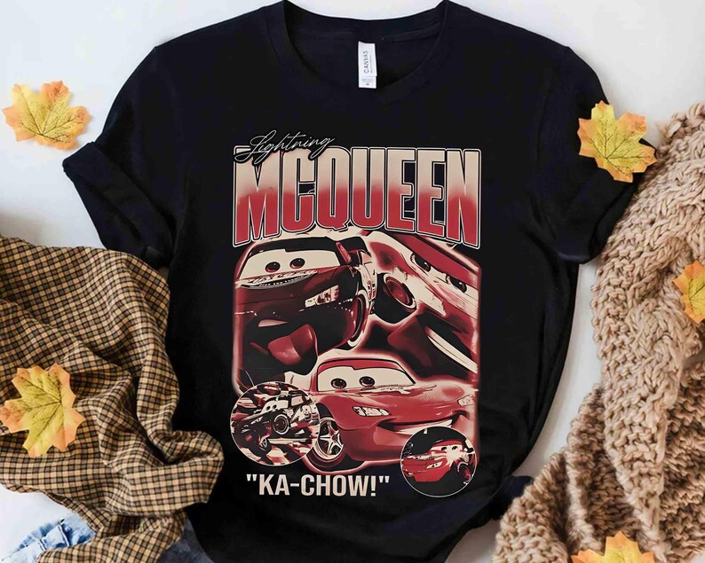 K&ouml;nnte beinhalten: Schwarzes T-Shirt mit einer Grafik von Lightning McQueen aus dem Film Cars. Das Design enth&auml;lt den Text "Lightning McQueen" in roter und wei&szlig;er Schrift sowie den Satz "KA-CHOW!" unter den Autobildern.