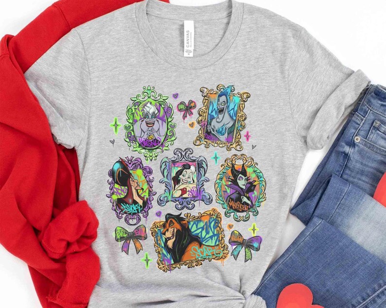 Puede incluir: Una camiseta gris claro con retratos enmarcados de villanos de Disney. Los retratos est&aacute;n en marcos ornamentados con acentos coloridos, incluyendo lazos y corazones. La camiseta est&aacute; hecha de un material suave.