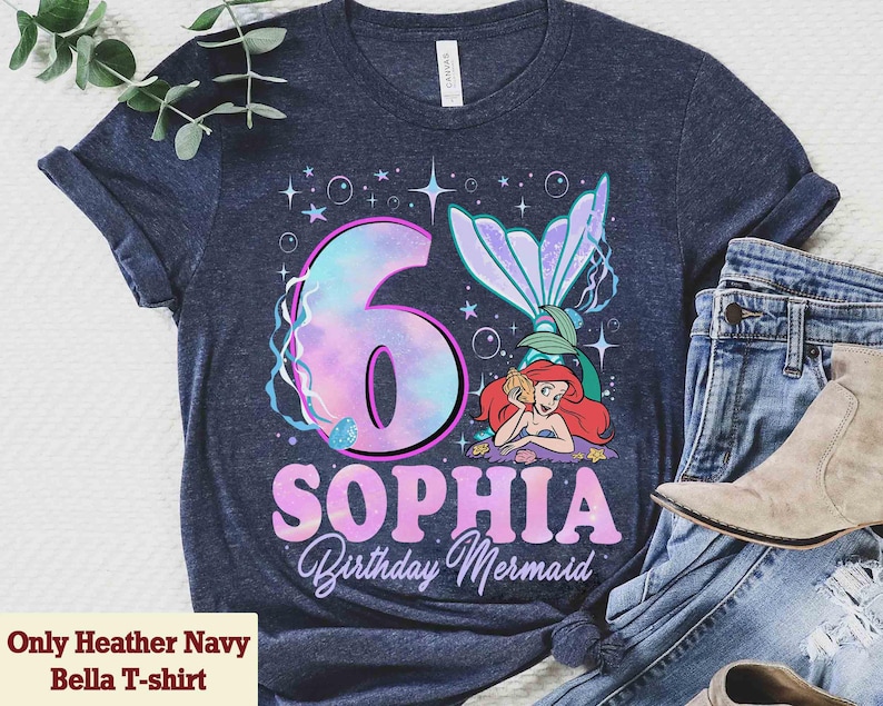Puede incluir: Camiseta Heather Navy Bella con un dise&ntilde;o de cumplea&ntilde;os de sirena. La camiseta presenta un gran n&uacute;mero 6 con efecto acuarela, el nombre "Sophia" y las palabras "Birthday Mermaid". Tambi&eacute;n aparece una sirena de dibujos animados.
