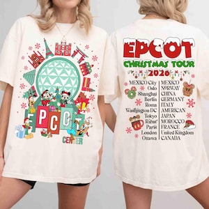 May include: An off-white t-shirt featuring a front graphic of the Epcot Centre with Disney characters and a back graphic listing the Epcot Christmas Tour 2024 with various global cities and countries, including Mexico, Norway, China, Germany, Italy, Japan, Morocco, France, United Kingdom, and Canada.