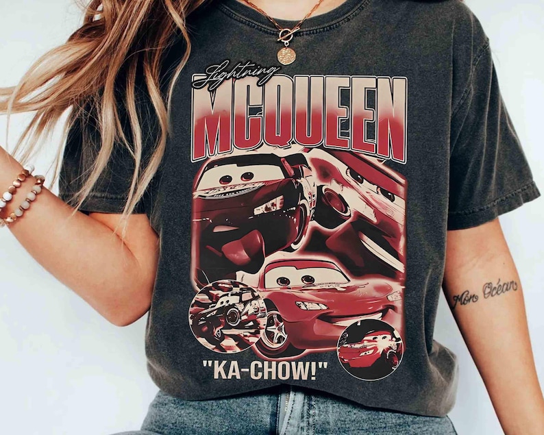 K&ouml;nnte beinhalten: Dunkelgraues T-Shirt mit Lightning McQueen aus dem Film Cars. Das Design zeigt das Bild der Figur und den Schriftzug "KA-CHOW!" in roter und wei&szlig;er Schrift. Das T-Shirt hat einen Vintage-Look.