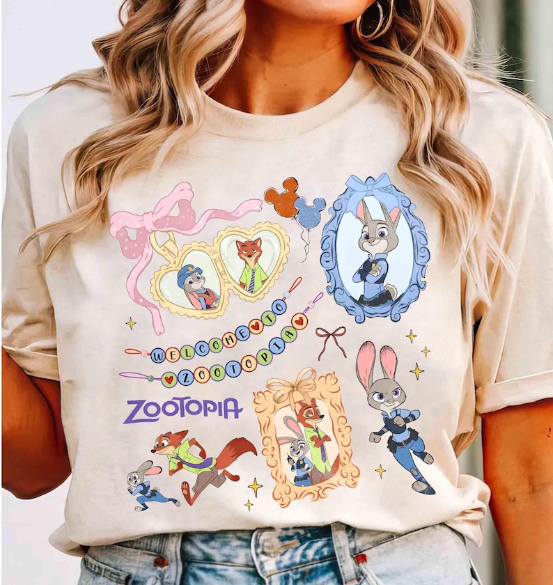 Puede incluir: Camiseta beige con dise&ntilde;o de Zootopia. El gr&aacute;fico incluye personajes de dibujos animados como Judy Hopps y Nick Wilde, enmarcados en elementos decorativos, con el texto "WELCOME TO ZOOOTPIA".