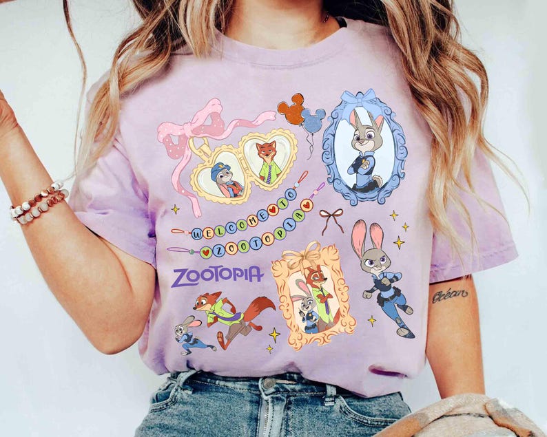 Puede incluir: Camiseta lila claro con personajes de Zootopia y el texto "WELCOME TO ZOOTOPIA". El dise&ntilde;o incluye retratos enmarcados de Judy Hopps y Nick Wilde, junto con otros gr&aacute;ficos de Zootopia.