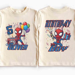 May include: Two cream-colored t-shirts featuring a Spider-Man graphic. One shirt shows Spider-Man with a birthday cake, balloons, and the name "Oliver". The other shirt says "BIRTHDAY BOY" with Spider-Man holding gifts and a party favor.