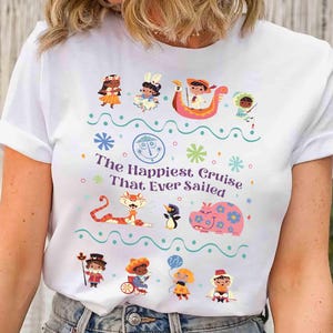 May include: White t-shirt featuring a colorful graphic with the text "The Happiest Cruise That Ever Sailed." The design includes cartoon characters, snowflakes, and a boat. A whimsical and fun design.