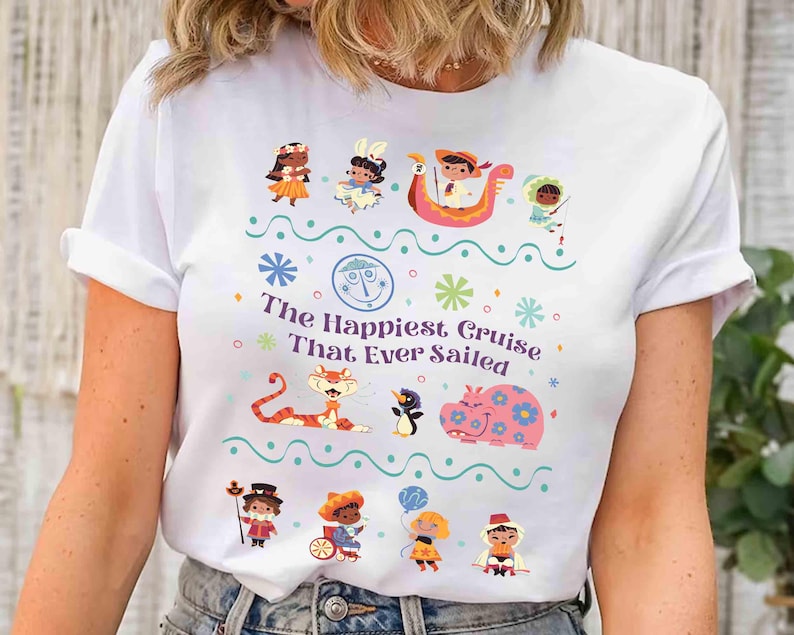 May include: White t-shirt featuring a colorful graphic with the text "The Happiest Cruise That Ever Sailed." The design includes cartoon characters, snowflakes, and a boat. A whimsical and fun design.