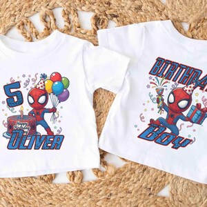 May include: Two white t-shirts with a Spider-Man graphic. One shirt says "5" with "Happy Birthday Oliver" and a cake. The other says "BIRTHDAY BOY". Both shirts feature the superhero in a party hat.