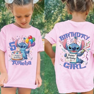 May include: Pink t-shirt featuring a cartoon character holding balloons and a birthday cake. The front of the shirt has the number 5 and the name "Amelia". The back of the shirt says "Birthday Girl" with the same cartoon character.