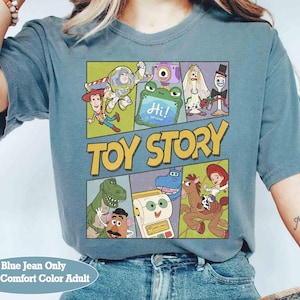 Puede incluir: Camiseta azul vaquero con un gr&aacute;fico colorido de personajes de Toy Story. El dise&ntilde;o incluye a Buzz Lightyear, Woody y otros personajes de la pel&iacute;cula animada. Las palabras "TOY STORY" se muestran de forma destacada.