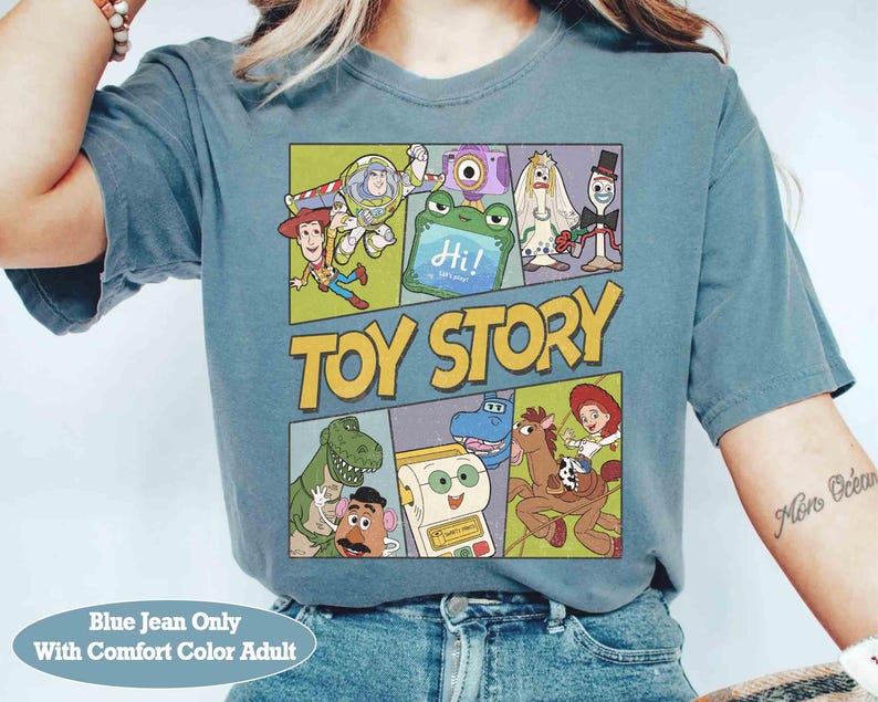 Puede incluir: Camiseta azul vaquero con un gr&aacute;fico colorido de personajes de Toy Story. El dise&ntilde;o incluye a Buzz Lightyear, Woody y otros personajes de la pel&iacute;cula animada. Las palabras "TOY STORY" se muestran de forma destacada.